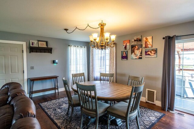 dining area featuring plenty of natural light, dark wood-style floors, visible vents, and a chandelier