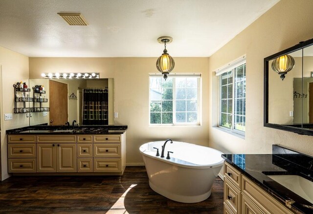 full bathroom featuring visible vents, a sink, a freestanding tub, and wood finished floors
