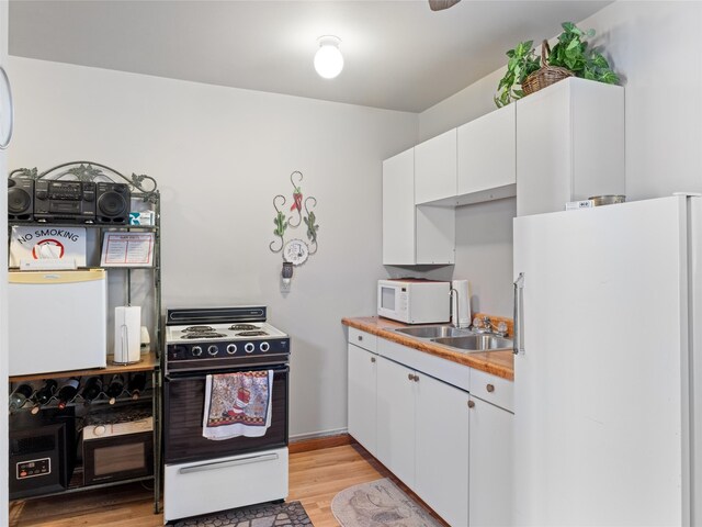 kitchen featuring sink, white cabinets, light wood-type flooring, and white appliances