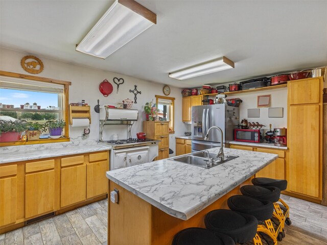 kitchen with sink, light hardwood / wood-style flooring, a center island with sink, and stainless steel refrigerator with ice dispenser