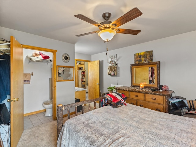 bedroom featuring ensuite bathroom, light tile patterned floors, and ceiling fan