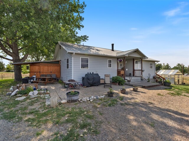 back of house with a fire pit, a shed, and a carport