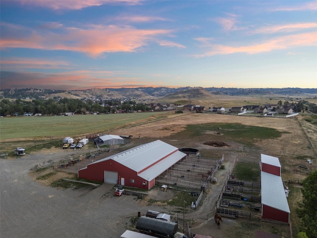 aerial view at dusk featuring a mountain view and a rural view