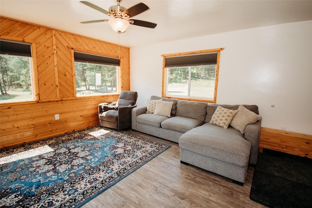 living room with plenty of natural light, ceiling fan, and wooden walls