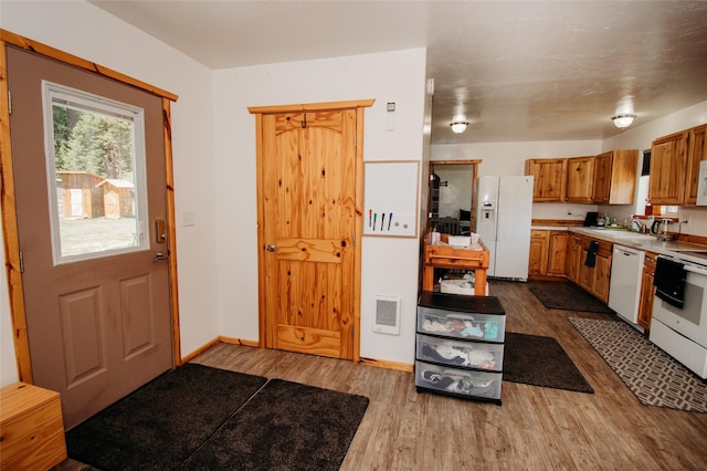 kitchen featuring wood-type flooring, white appliances, and sink