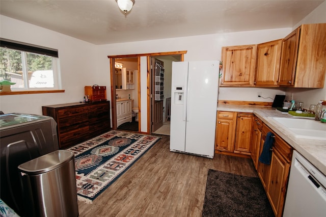 kitchen with light wood-type flooring, white appliances, washer / clothes dryer, and sink