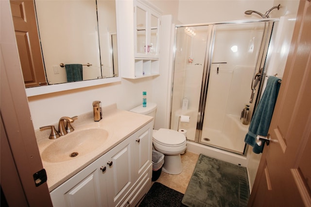 bathroom featuring tile patterned flooring, vanity, toilet, and a shower with door