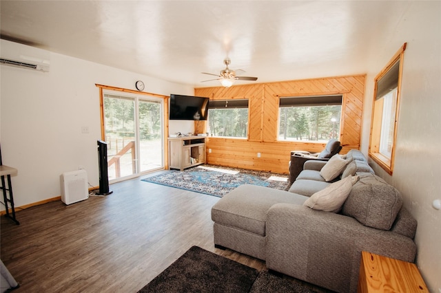 living room featuring wooden walls, a wealth of natural light, ceiling fan, and a wall unit AC