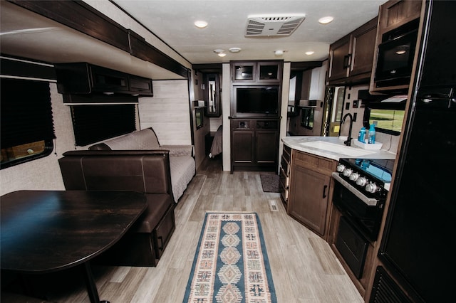 kitchen featuring black appliances, dark brown cabinetry, sink, and light hardwood / wood-style flooring