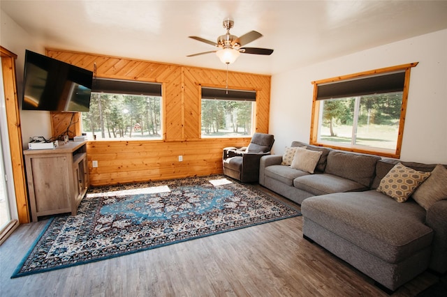 living room featuring ceiling fan, dark hardwood / wood-style flooring, and wooden walls