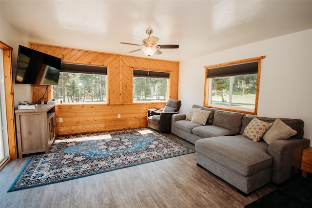 living room with wood walls, ceiling fan, and hardwood / wood-style flooring