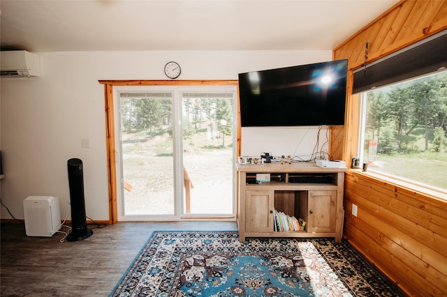 living room with a wall mounted air conditioner, dark hardwood / wood-style floors, and wood walls