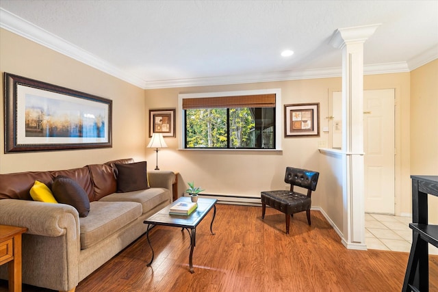 living room featuring light hardwood / wood-style floors, ornate columns, a baseboard radiator, and crown molding