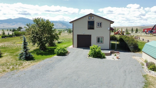 exterior space featuring a garage, gravel driveway, and a mountain view