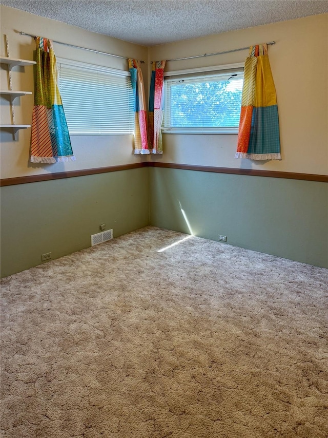 carpeted empty room featuring visible vents and a textured ceiling