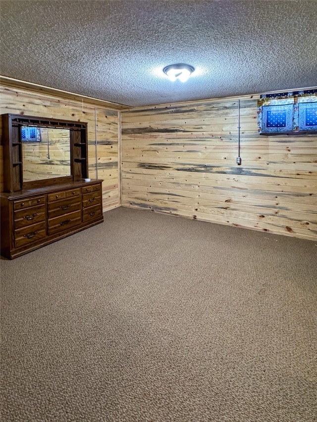 finished basement with carpet floors, wooden walls, and a textured ceiling