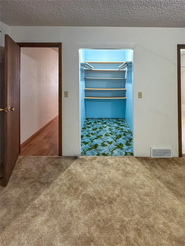 interior space featuring visible vents, a textured ceiling, and carpet flooring