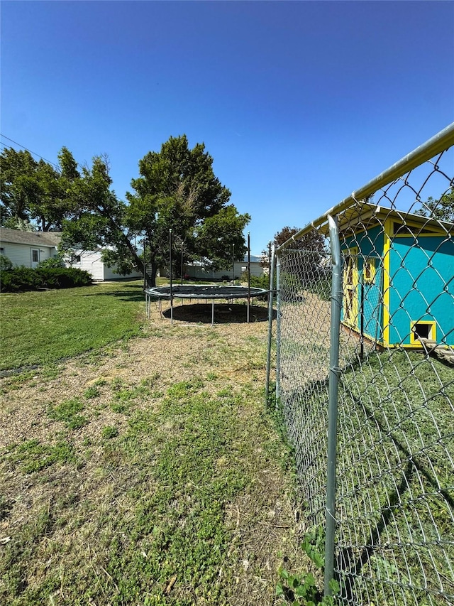 view of yard with a trampoline and fence