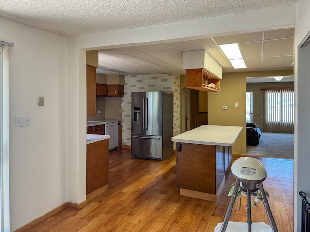 kitchen featuring brown cabinets, light countertops, white dishwasher, light wood-type flooring, and stainless steel fridge with ice dispenser