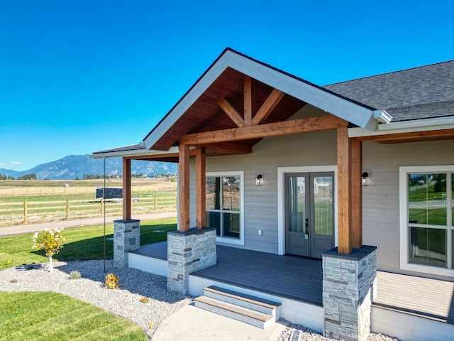 view of exterior entry with french doors, a mountain view, a rural view, and a yard