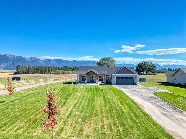 ranch-style house with a mountain view, a garage, a front lawn, and a rural view