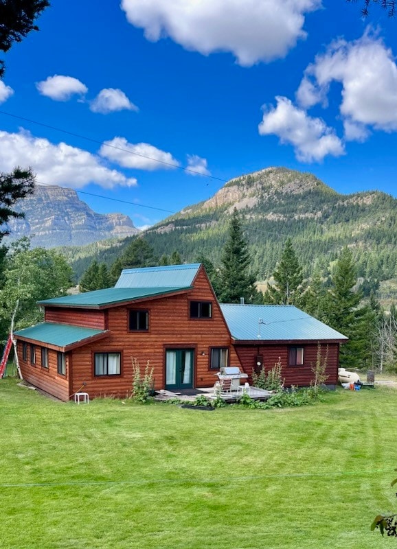 back of property with a mountain view and a yard