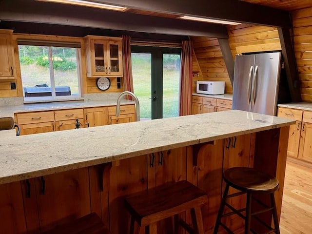 kitchen featuring freestanding refrigerator, glass insert cabinets, a healthy amount of sunlight, and white microwave