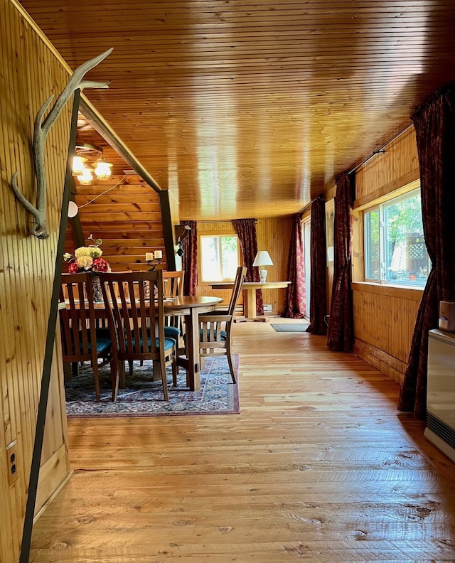 dining room with wooden walls, wood finished floors, and wooden ceiling