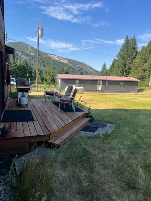 deck with grilling area, a mountain view, and a yard
