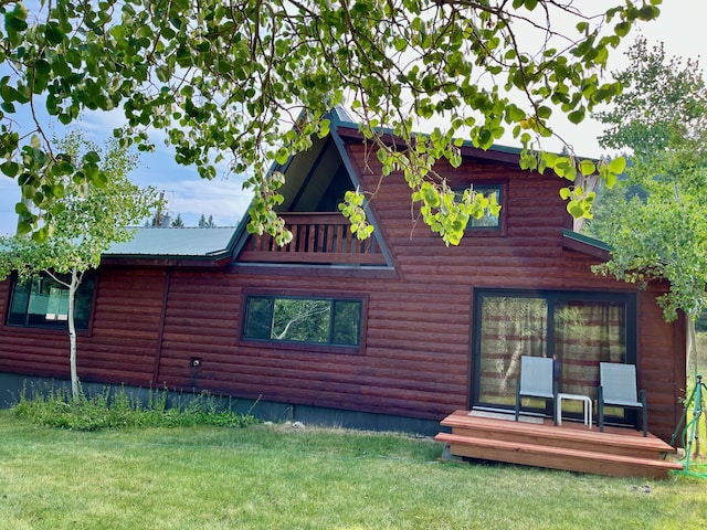 back of property with a wooden deck, a yard, and faux log siding