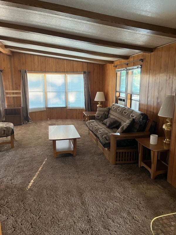 unfurnished living room featuring beamed ceiling, wooden walls, and carpet flooring