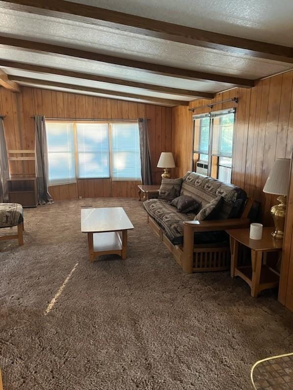 living room featuring wooden walls, carpet floors, a textured ceiling, and beamed ceiling