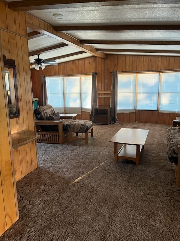 living room featuring ceiling fan, wooden walls, and carpet floors