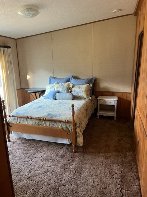 bedroom featuring a textured ceiling, wooden walls, and carpet flooring