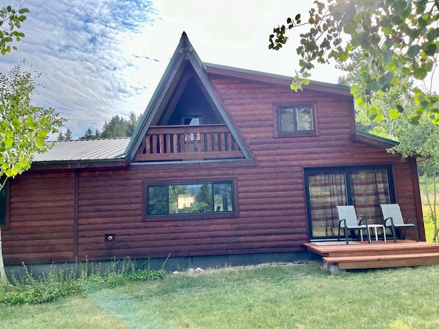 back of house featuring a lawn, faux log siding, and a wooden deck