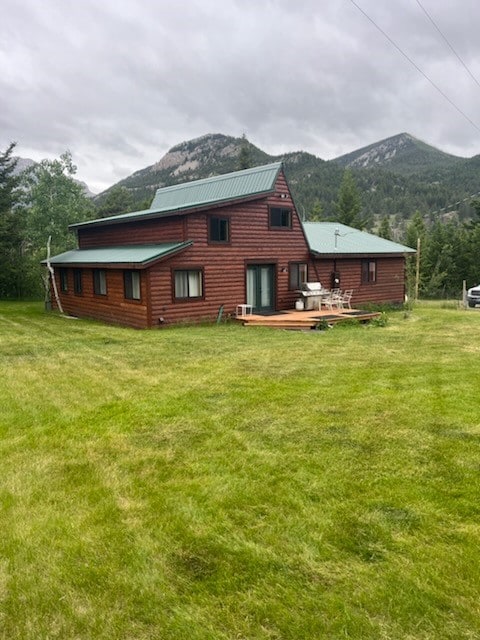 back of house with a deck with mountain view and a lawn