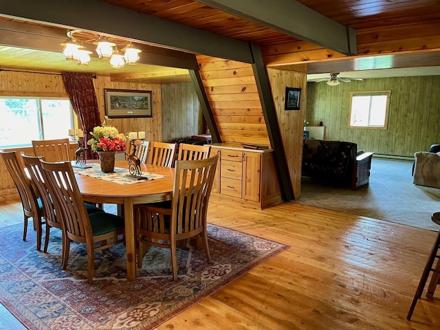 dining area featuring hardwood / wood-style floors, ceiling fan with notable chandelier, plenty of natural light, and wooden walls