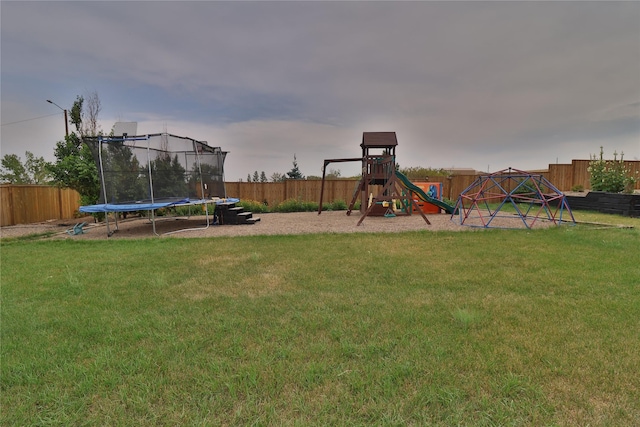 view of playground with a trampoline, a yard, and fence