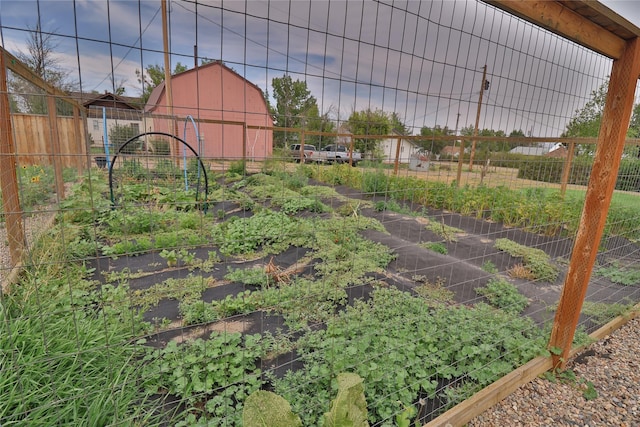 view of yard featuring a garden, fence, and an outbuilding