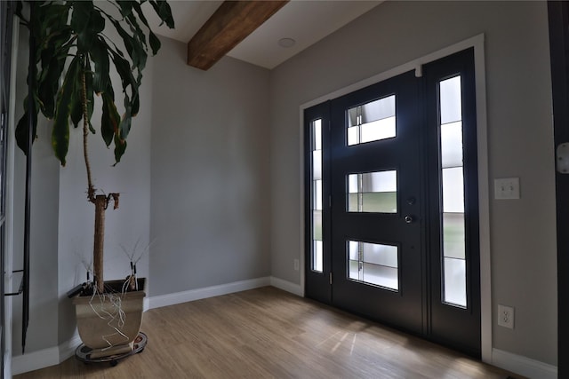 foyer entrance with baseboards, beam ceiling, and wood finished floors