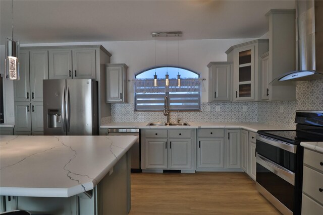 kitchen featuring pendant lighting, stainless steel appliances, sink, and wall chimney range hood