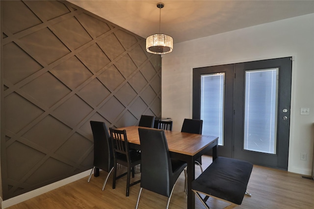 dining area with light wood-type flooring, an accent wall, baseboards, and a decorative wall