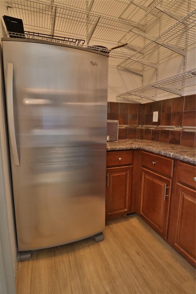 kitchen featuring dark stone countertops, light wood-type flooring, and decorative backsplash