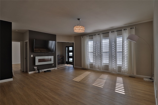 unfurnished living room with hardwood / wood-style flooring, a large fireplace, and a chandelier