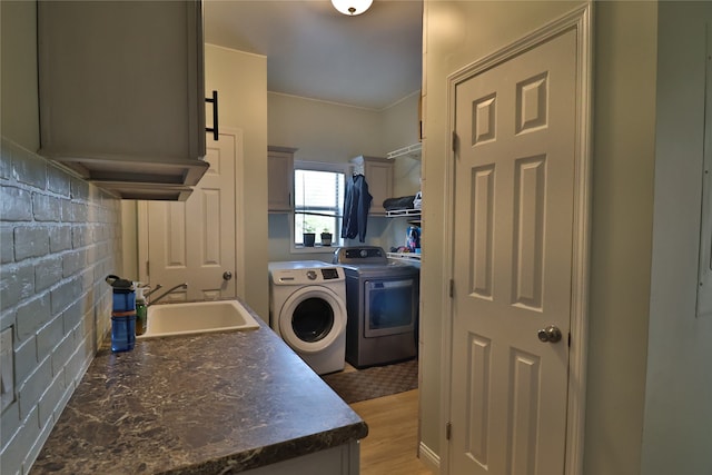 laundry area with sink, light hardwood / wood-style floors, and washing machine and dryer