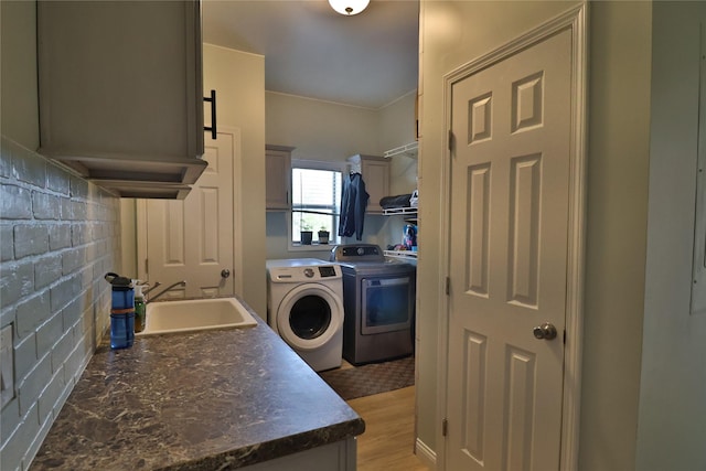 kitchen featuring a sink, light wood finished floors, dark countertops, and washing machine and clothes dryer