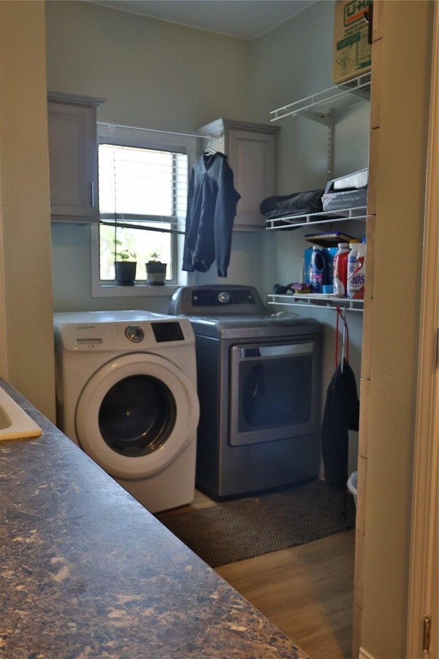 laundry room with hardwood / wood-style flooring, cabinets, and washer and clothes dryer