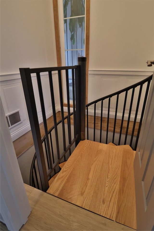 staircase with a wainscoted wall, visible vents, and a decorative wall