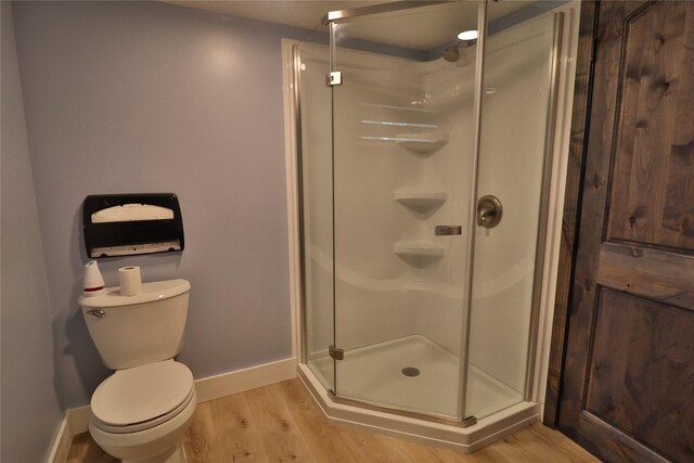 bathroom featuring wood-type flooring, toilet, and a shower with shower door