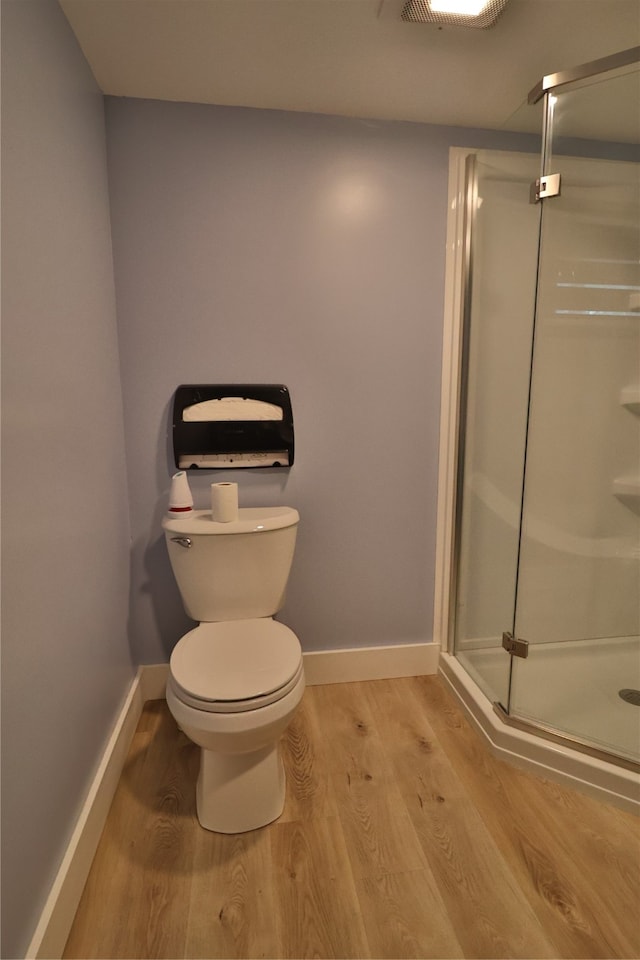 bathroom featuring hardwood / wood-style flooring, toilet, and walk in shower